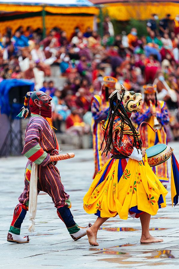 Atsara strutting behind masked cham drummers in front of the festival crowd