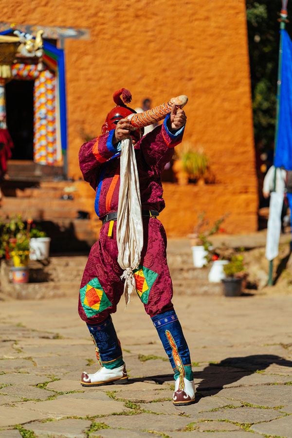 Atsara raising the ritual wooden phallus with a ceremonial scarf outside a temple